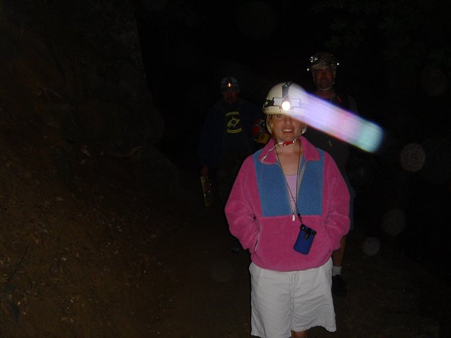 Cave Explorers with Headlamps in Dark Tunnel