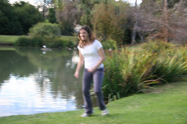 Young Woman Walking Beside a Tranquil Pond