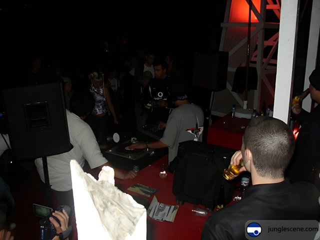 Nightlife in Ensenada Caption: A group of 11 people gather around a table with a DJ as speakers blare music in a nightclub in Ensenada, Baja California, Mexico in 2002.