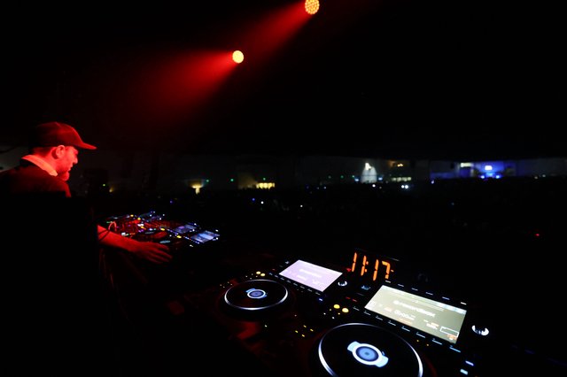 DJ Drops Bass Under Red Stage Lights at Night