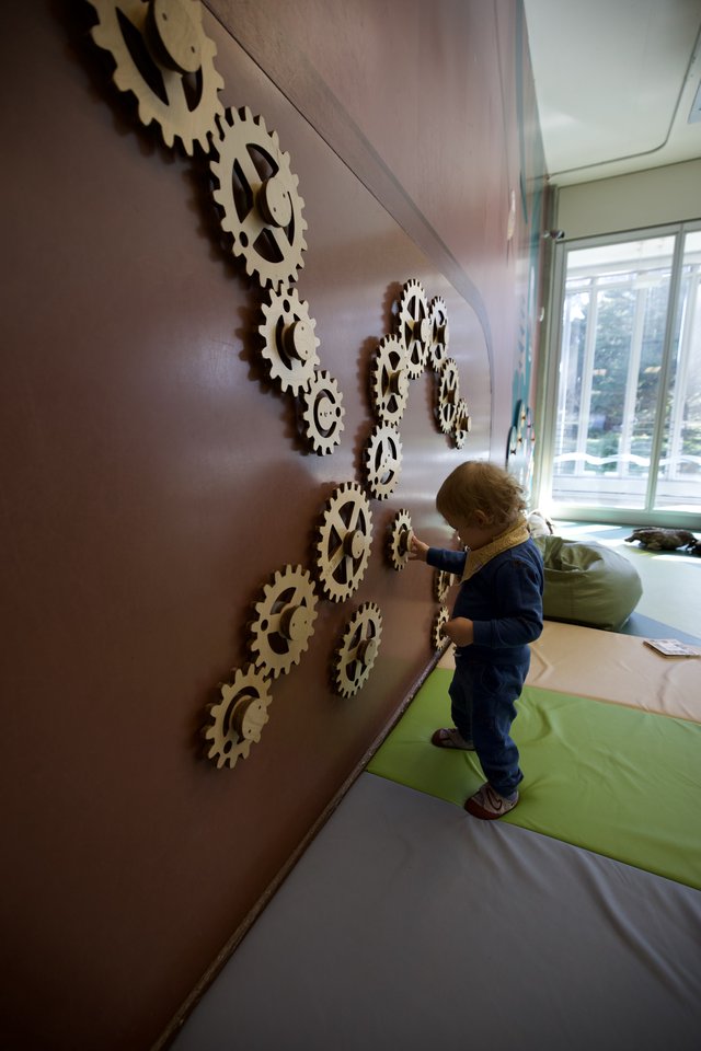 Child Exploring Interactive Gear Wall Installation