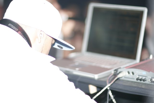 Man in White Shirt Works on Laptop
