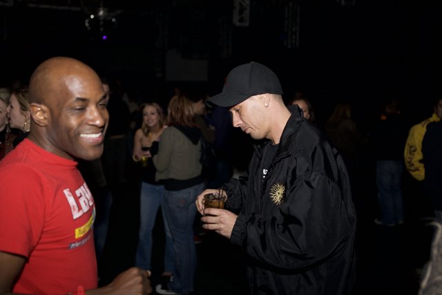 Man in Red Shirt and Black Hat Sips Drink at Funky Funktion Party