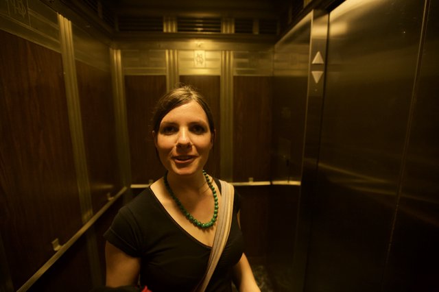 Woman Smiling in Vintage Wood-Paneled Elevator