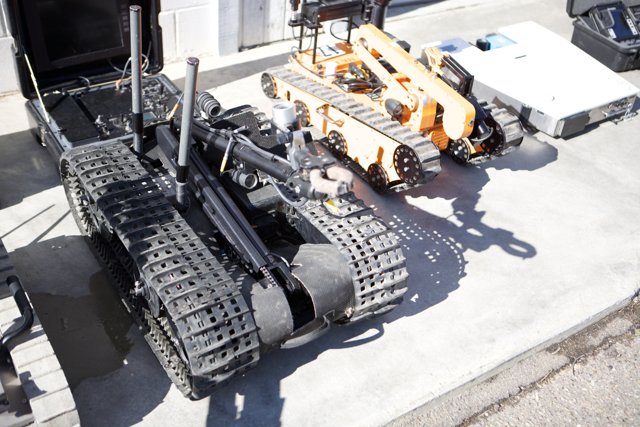 Machine Robot Among Military Equipment