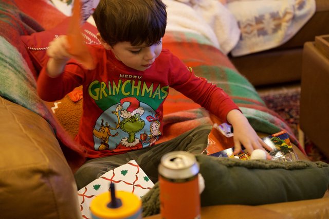 Child Opening Christmas Presents in Grinch Pajamas
