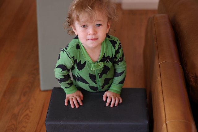 Toddler in Green Bat Pajamas on Ottoman