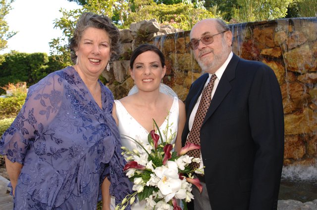 Bride Poses With Parents at Outdoor Wedding