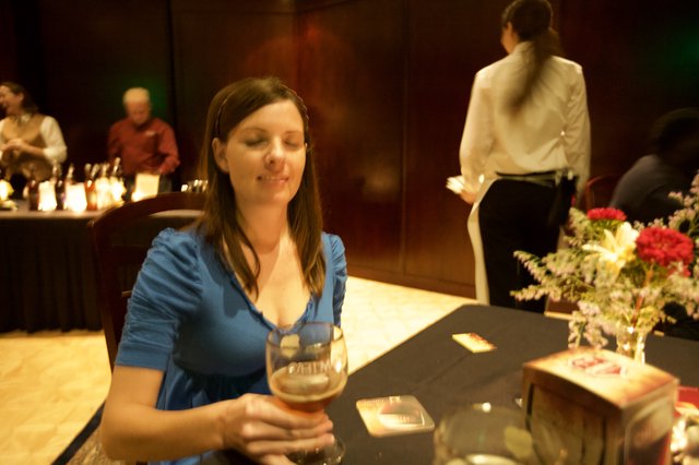 Woman Smiling Over Craft Beer at Evening Event