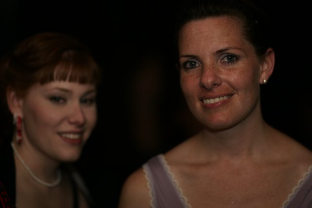 Two Women Smiling at a Dimly Lit Evening Event