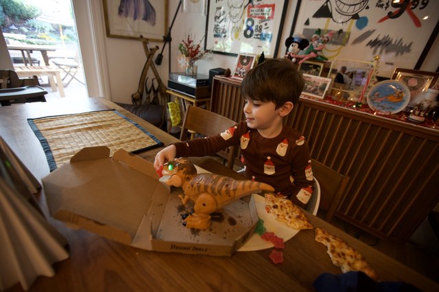 Child Enjoying Pizza with Dinosaur Toy on Christmas