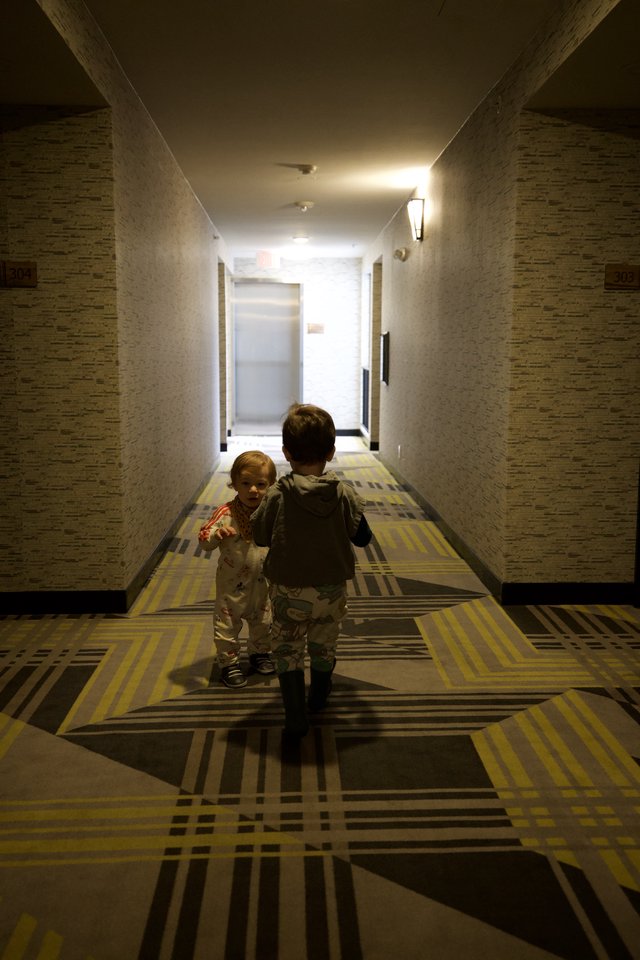 Two Children Walking Down Hotel Corridor at Dusk