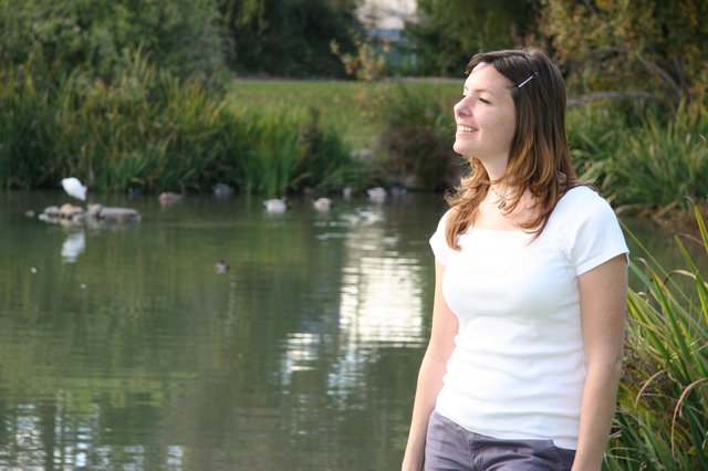 Joyful Woman Smiling by a Tranquil Park Pond