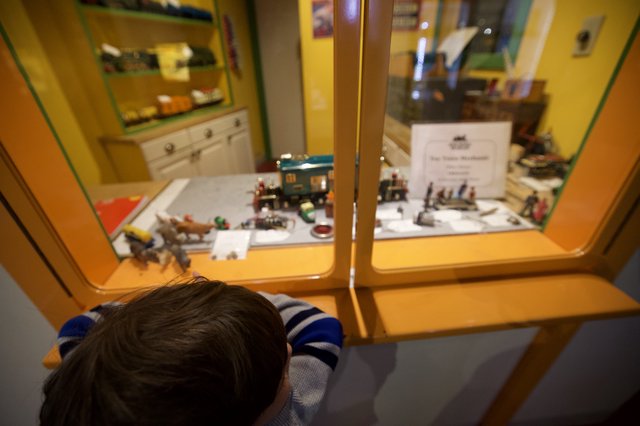 Child Examining Miniature Train Display at Museum