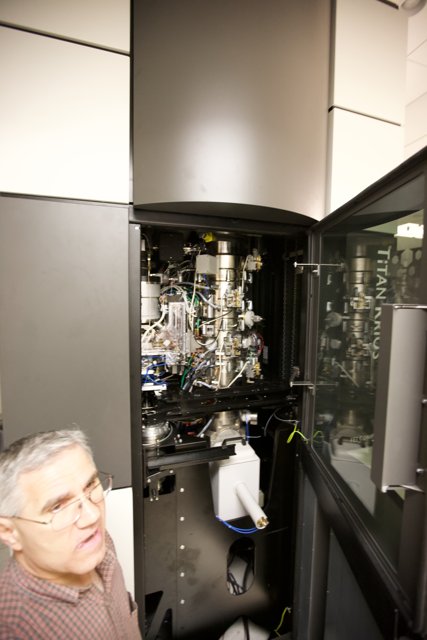 Man Examining Optical Equipment in a Technical Setting