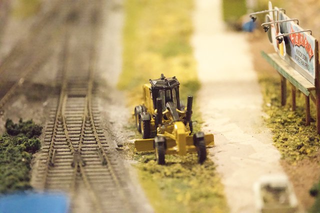 Miniature Road Grader Beside Model Railroad Tracks