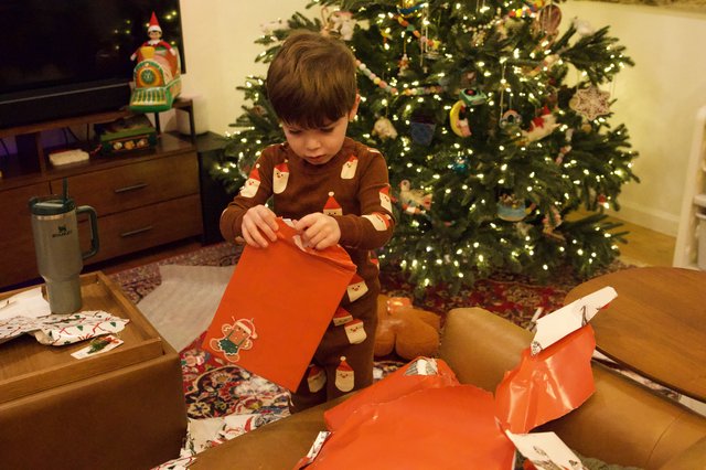 Young Boy Opening Christmas Gifts by Decorated Tree