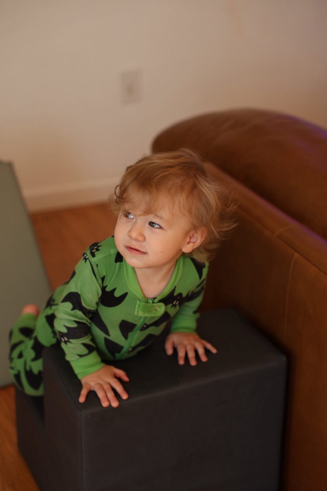 Toddler in Green Dinosaur Pajamas on Chair