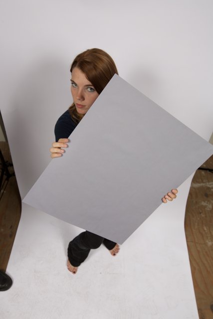 Standing Strong Caption: A woman holds a large plywood board, confident and determined.