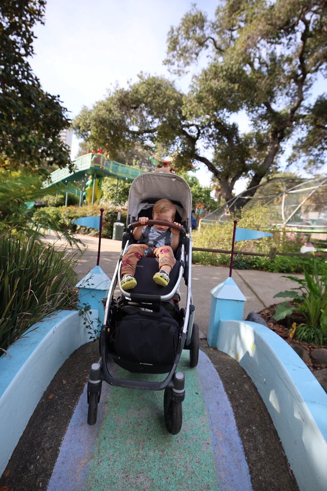 Child in Stroller on Whimsical Garden Bridge Path