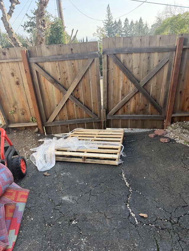 Weathered Wooden Gate with Wooden Pallet in Driveway