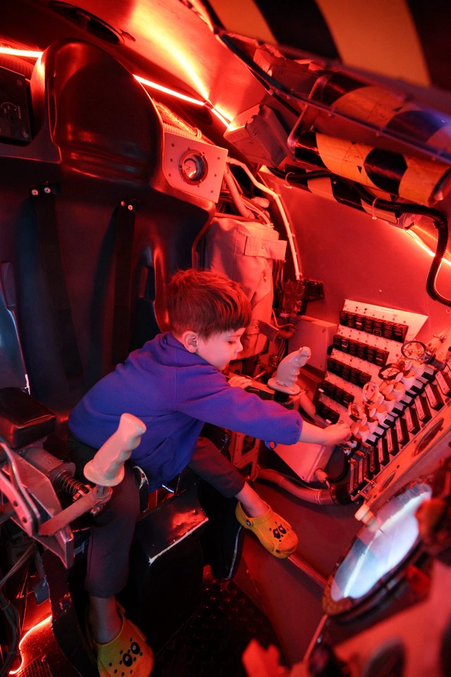 Young Explorer in Submarine Control Room Under Red Lights