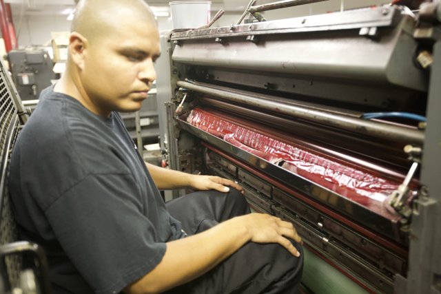 Hard At Work: Man Operating Printing Machine in Factory