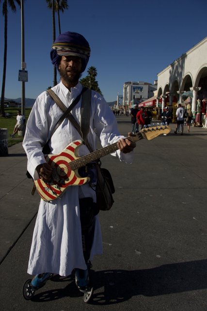 Turbaned musician strums the guitar under a Palm tree