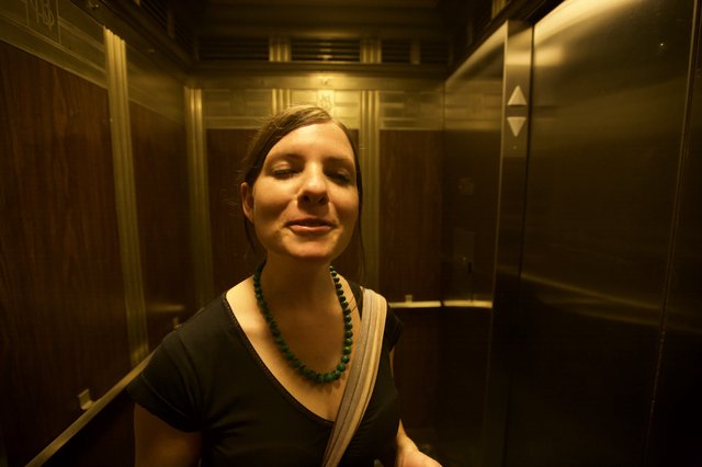 Serene Woman in Golden-Lit Vintage Elevator