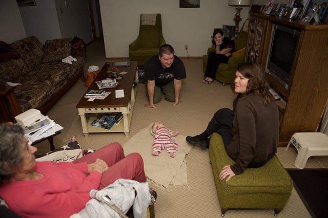Family Gathering Around Newborn Baby in Living Room