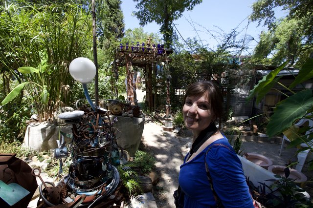 Woman Smiling Among Eclectic Junk Art Garden