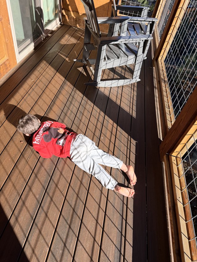 Child Soaking Up Winter Sun on Wooden Deck