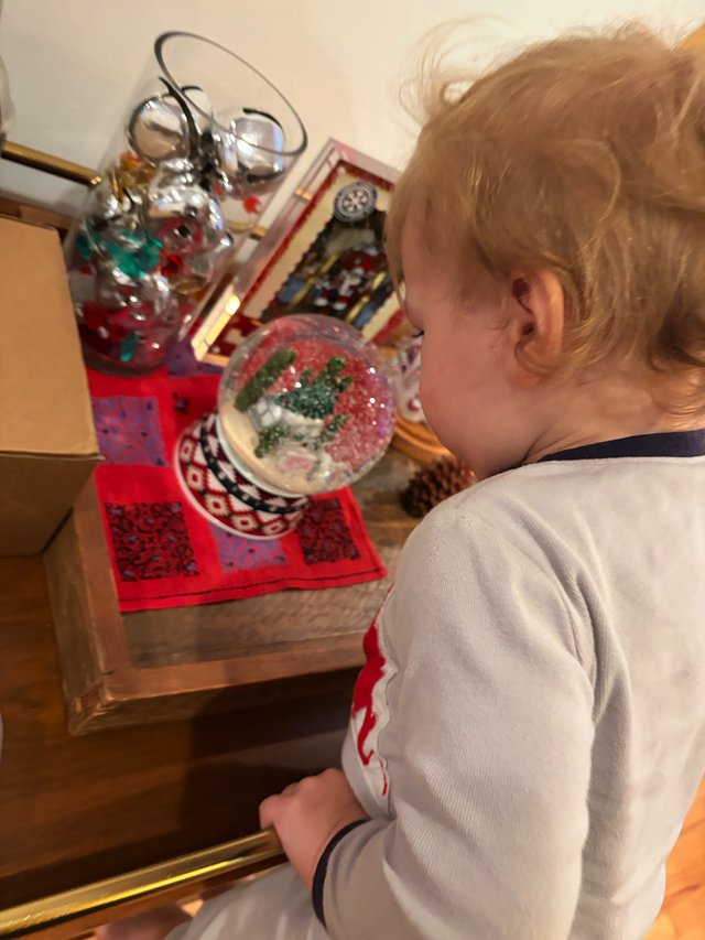 Child Admiring Snow Globe Collection at Bedside