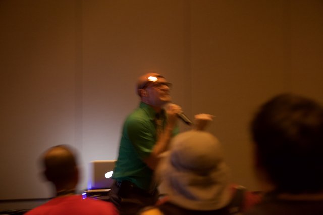 Green-Shirted Man Holds Microphone at Seminar