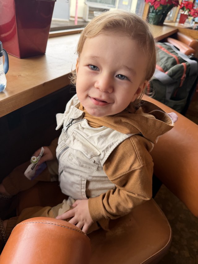Joyful Toddler Smiling at Café Table