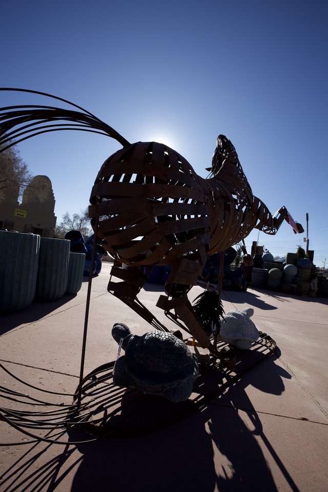 Metallic Rooster Sculpture Silhouetted Against Bright Sun