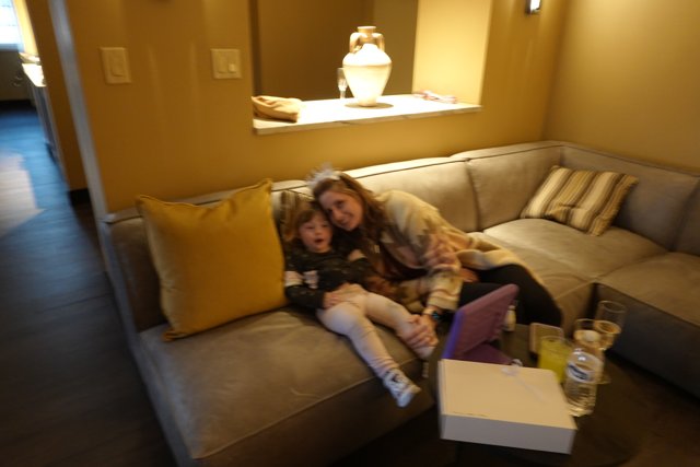 Cozy Afternoon in Santa Fe Caption: A mother and her daughter enjoying a relaxing moment on a comfortable couch in their hotel room in Santa Fe, surrounded by beautiful architecture and home decor.