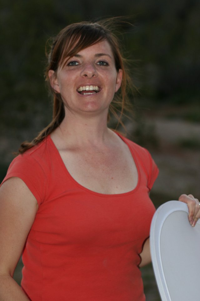 Laughing Woman in Red Top Holds Frisbee Outdoors