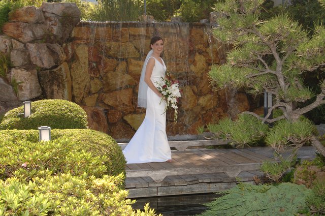 Bride Poses Before Stone Waterfall in Japanese Garden