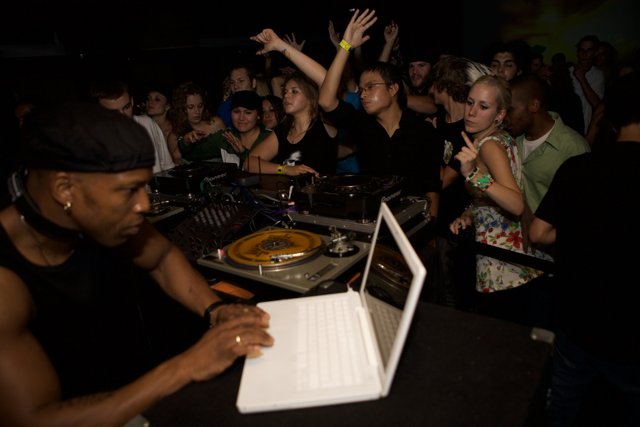 Man in Black Shirt Working on Laptop at Nightclub