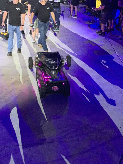 Men Walk with Robot on Las Vegas Speedway
