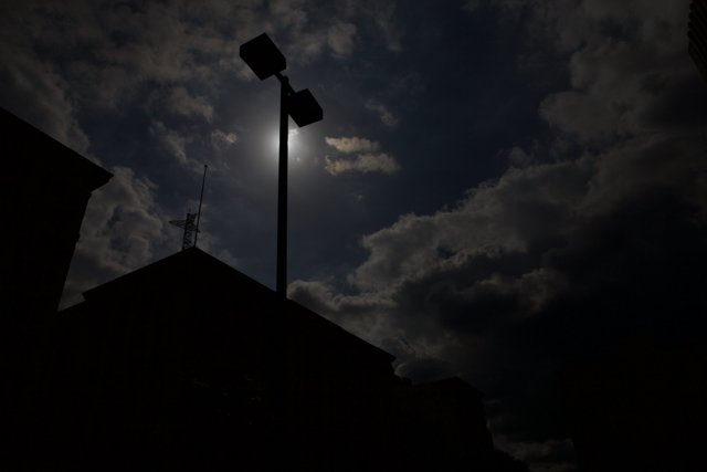 Silhouette of a Lamppost Against Cloudy Night Sky
