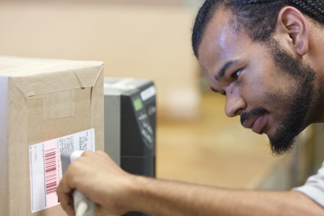 Curious Man Examining Barcode on Cardboard Box