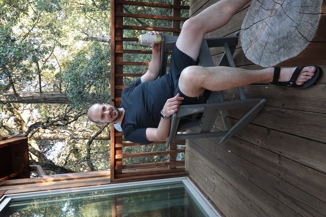Man Relaxing on Wooden Deck Among Trees