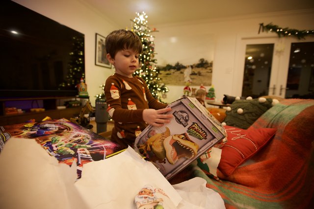 Child Opening Christmas Present with Dinosaur Book