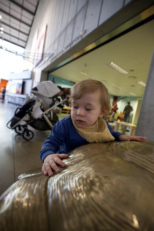 Young Child Exploring Bronze Sculpture at Museum