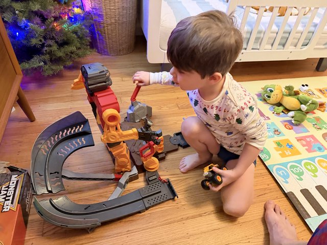 Toddler Playing with Monster Truck Toy Track Set at Christmas