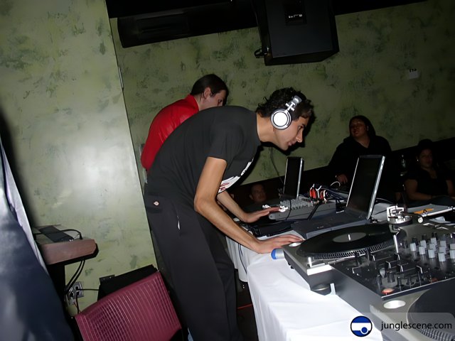 Grooving to the Beats Caption: A man in headphones enjoying the music at a party with a DJ and speakers.
