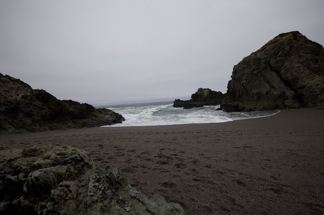 Rugged Cove Where Dark Sand Meets Crashing Pacific Waves