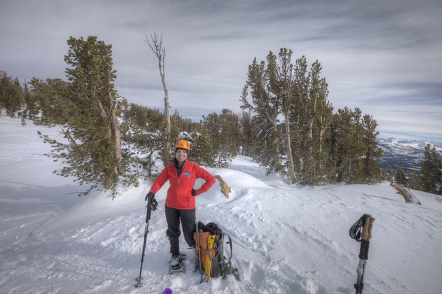 Smiling Mountaineer Rests Atop Snowy Sierra Summit